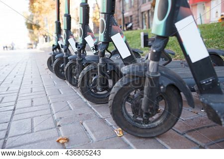 Close Up Of Front Wheels Of Electric Scooters Lined Up On City Street