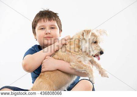 Young Boy Holds His Dog In His Arms And Strokes It. Subject Isolated From The Background.