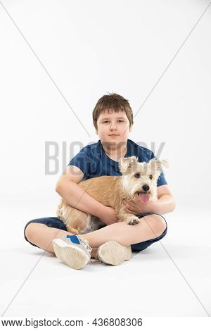 A Young Boy Sits On A White Background And In His Hands He Holds His Beloved Dog.