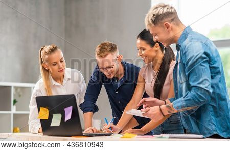 Team of young and confident startupers is working at the table in the office, discussing the strategy and development plan of the company. Business, innovation, brainstorming and teamwork.