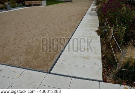 Park Square With Gravel Compacted Paths And Concrete Sidewalk. A Metal Slot Gutter Is Used For Drain