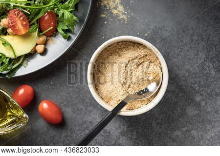 Nutritional Yeast Flakes In Ceramic Bowl On Dark Background. Dietary Supplement, Superfood. Top View