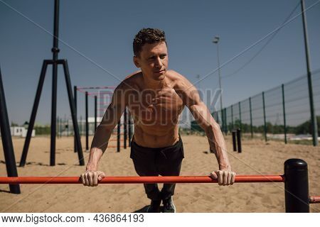Young Man Doing Calisthenics Outdoors. Man Doing Pull-ups In The Street. Guy Working Out On Pull-up 