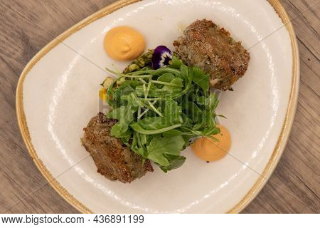 Overhead View Of Hearty Plate Of Roasted And Fried Crab Cakes With A Dallop Of Sauce And Arrranged O