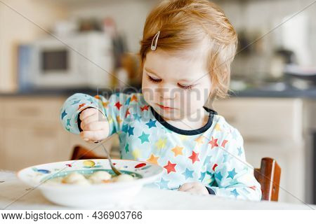 Adorable Baby Girl Eating From Spoon Vegetable Noodle Soup. Food, Child, Feeding And Development Con