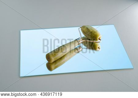 Green Jade Roller On White Background And Mirror With Sky Reflection. Spa And Wellness Concept