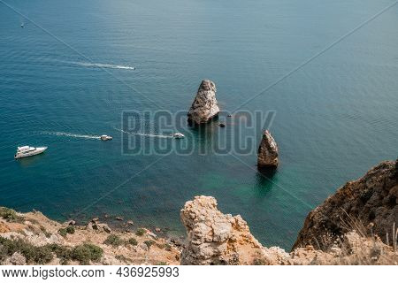Two Rocks Stick Out Of The Water In The Middle Of The Turquoise Sea. Scenic Ocean View. Speed Boat S