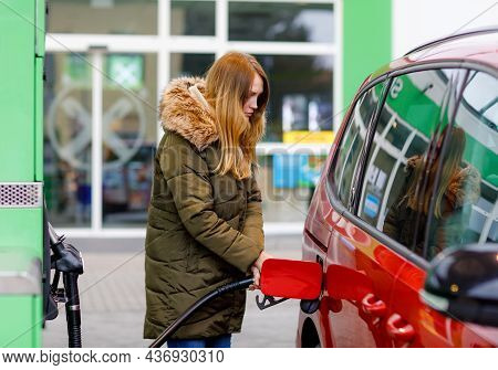 Young Caucasian Woman At Self-service Gas Station, Hold Fuel Nozzle And Refuel The Car With Petrol, 