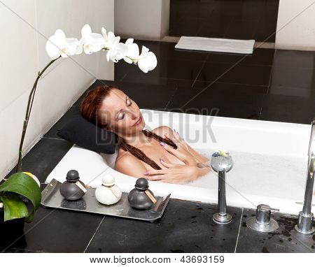 ผู้หญิงวางใน soapsuds ในการอาบน้ำที่เต็ม