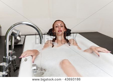 ผู้หญิงวางใน soapsuds ในการอาบน้ำที่เต็ม