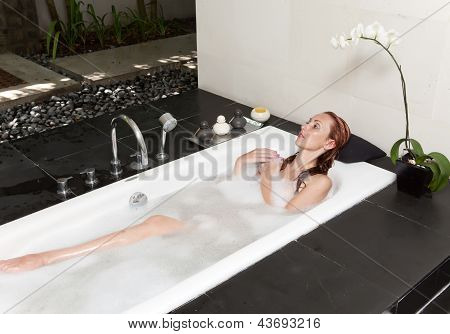ผู้หญิงวางใน soapsuds ในการอาบน้ำที่เต็ม