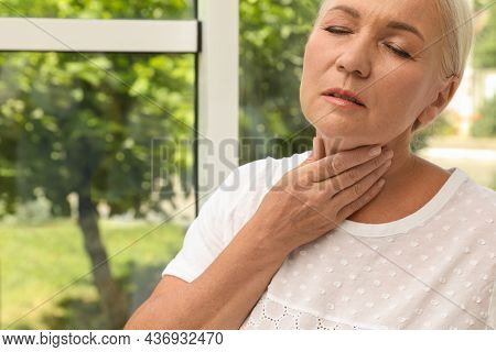 Mature Woman Doing Thyroid Self Examination Near Window, Closeup. Space For Text