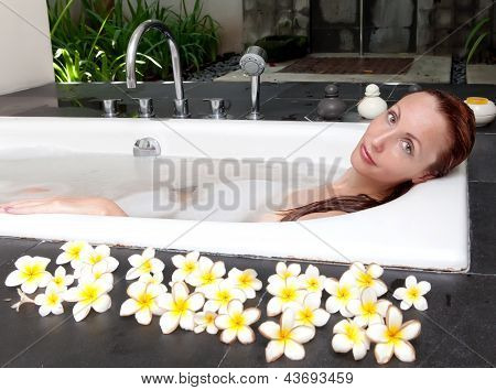 ผู้หญิงวางใน soapsuds ในการอาบน้ำที่เต็ม