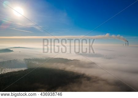 Aerial View Of Winter Landscape With Foggy Countryside And Distant Factory Pipes Emmiting Black Dirt