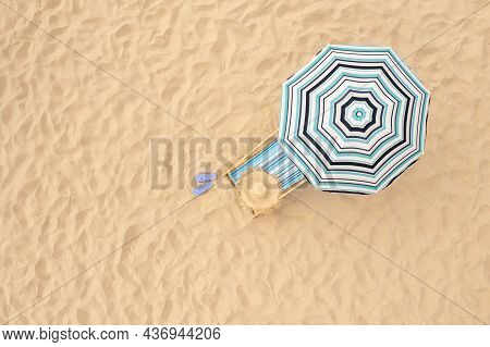 Striped Beach Umbrella Near Sunbed With Vacationist's Stuff On Sandy Coast, Aerial View. Space For T