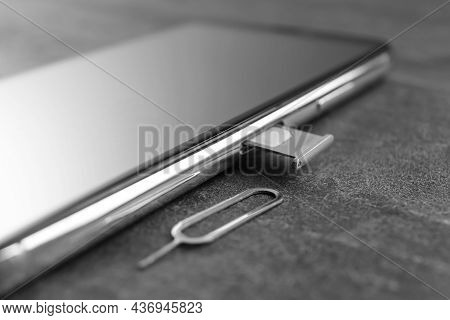 Mobile Phone With Sim Card In Tray And Ejector Tool On Grey Table, Closeup