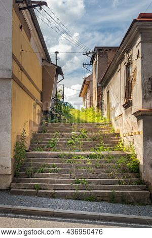 Dirty Unmaintained Side Street With Grass-covered Stairs Between Buildings, Blue Sky With White Clou