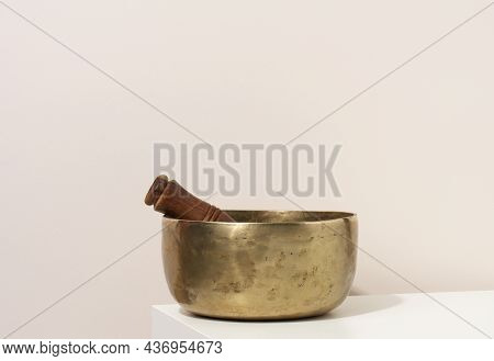Copper Singing Bowl And Wooden Clapper On A White Table. Musical Instrument For Meditation, Relaxati