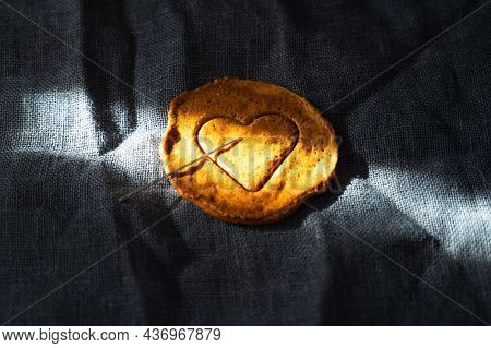 Brown sugar caramel candy cookies with a metal needle in the shape of a heart. Concept of survival game