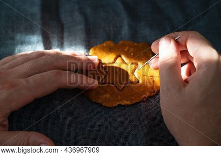 Men's hands closeup scratch and break brown sugar caramel candy cookies with a metal needle in the shape of a star. Concept of survival game