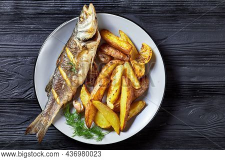 Whole Roasted Sea Bass Fish Served On A Plate With Sea Salt, Dill, Baked Potato Wedges Horseradish O