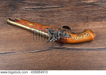 A Replica Of An Old Muzzle-loaded Pistol On A Wooden Background.