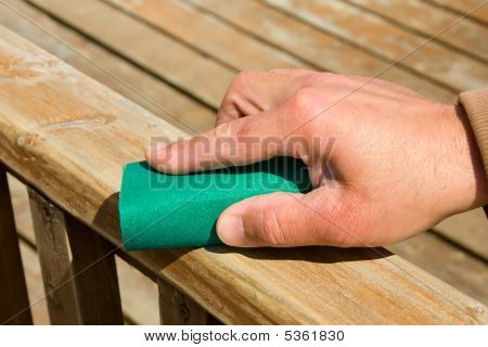 Hand med Sand papper och trä yta