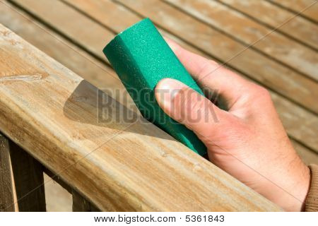 Hand med Sand papper och trä yta