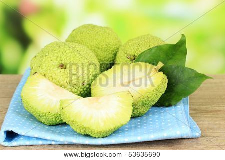 Osage Orange fruits (Maclura pomifera) in basket, on wooden table, on nature background