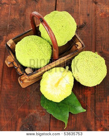Osage Orange fruits (Maclura pomifera) in basket, on wooden background
