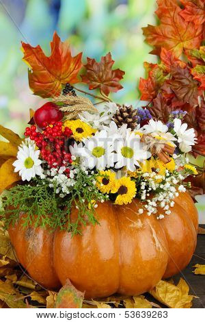 Beautiful autumn composition in pumpkin with yellow leaves on table on bright background