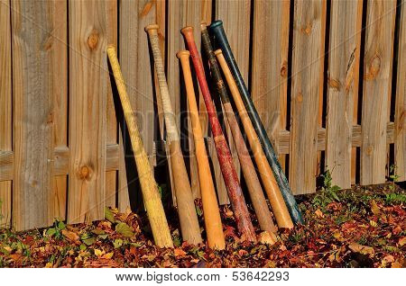 Baseball bats lean on a  fence
