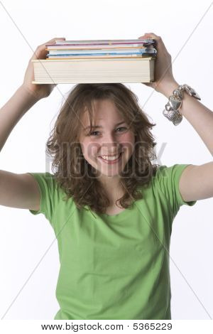 Heureuse jeune adolescente transportant une Pile de livres sur la tête