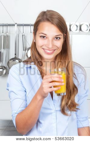 Laughing woman in the kitchen drinking orange juice
