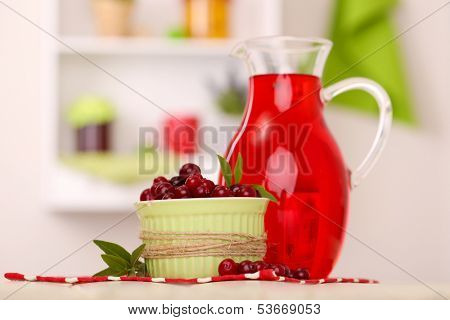 Pitcher and glass of cranberry juice with red cranberries on table 