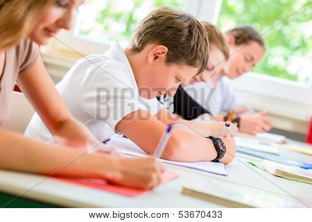 Students or pupils of school class writing an exam test in classroom concentrating on their work