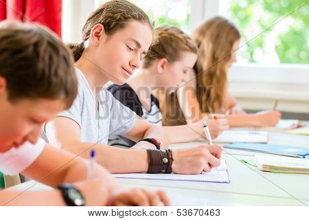 Students or pupils of school class writing an exam test in classroom concentrating on their work