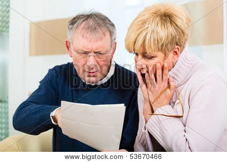 Two elderly people have received a letter, maybe it's a reminder or a Bill, but most likely it is the tax assessment notice