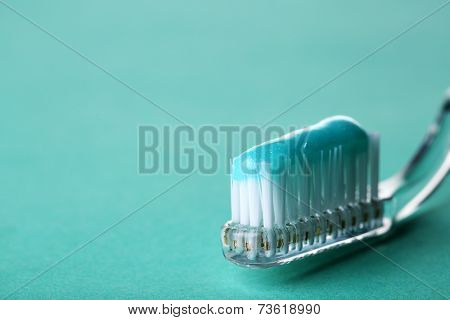 Toothbrush with blue toothpaste on color background
