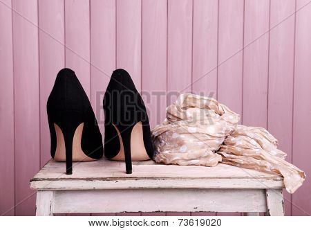 Black women shoes and scarf on bench on wooden background