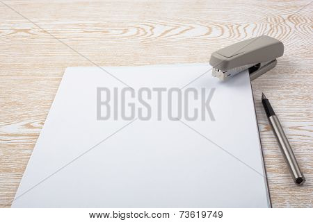 Sheets of paper and office accessories on wooden texture.