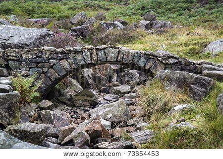 Old Ancient Packhorse Bridge Over Mountain Stream In Autumn