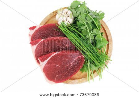 uncooked meat : raw fresh beef pork fillet ready to cooking with garlic and green stuff over wood isolated over white background