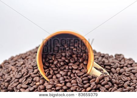 ceramic orange mug on a pile of roasted coffee beans