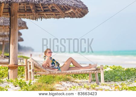 Woman sunbathing on tropical beach.