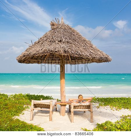 Woman sunbathing on tropical beach.