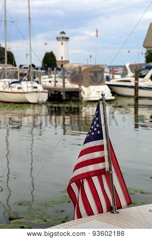 American Flag In Harbor With Boats And Lighthouse