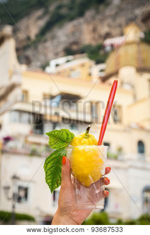 Girl's hand holding a glass with lemon ice cream.