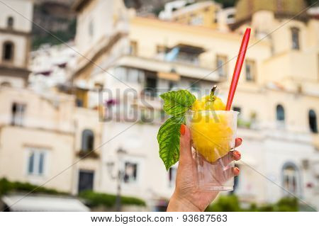Girl's hand holding a glass with lemon ice cream.