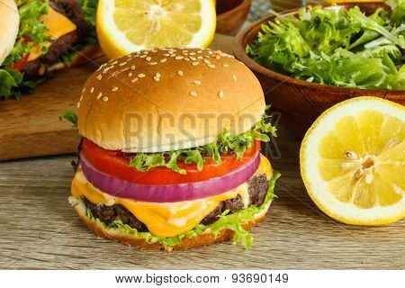 Cheeseburger with lettuce tomato and onion on a wooden background